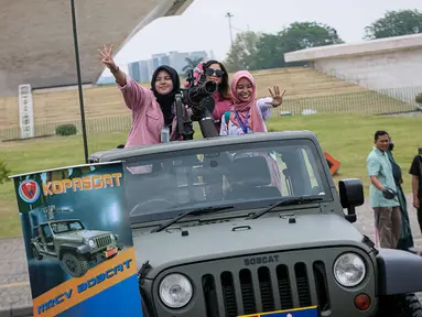 Warga berfoto di atas kendaraan milik TNI saat pameran alat utama senjata (alutsista) di Lapangan Monumen Nasional (Monas) Jakarta, Minggu (24/9/2023). (Liputan6.com/Faizal Fanani)