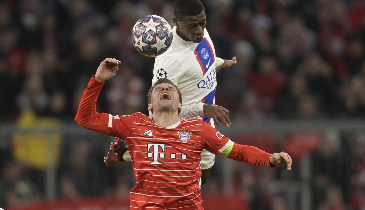 Penyerang Bayern Munchen, Thomas Mueller melompat berebut bola dengan pemain PSG, Nuno Mendes pada pertandingan leg 2 babak 16 besar Liga Champions di Allianz Arena di Munich, Jerman, Kamis (9/3/2023). Bayern menang atas PSG dengan 2-0. (AP Photo/Matthias Schrader)