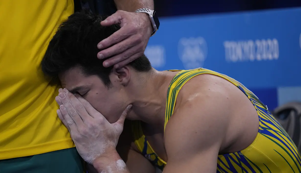 Pesenam Brasil, Arthur Mariano dihibur oleh pelatihnya selama kualifikasi senam artistik putraOlimpiade Tokyo 2020, di Tokyo pada 24 Juli 2021. (AP Photo/Gregory Bull)