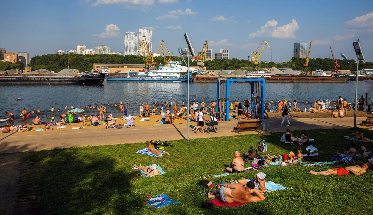 Orang-orang berjemur di tepi Sungai Moskva pada musim panas di Moskow, Rusia, Selasa (13/7/2021). Moskow dilanda gelombang panas bersejarah pada akhir Juni, dengan suhu mencapai rekor 120 tahun. (DIMITAR DILKOFF/AFP)