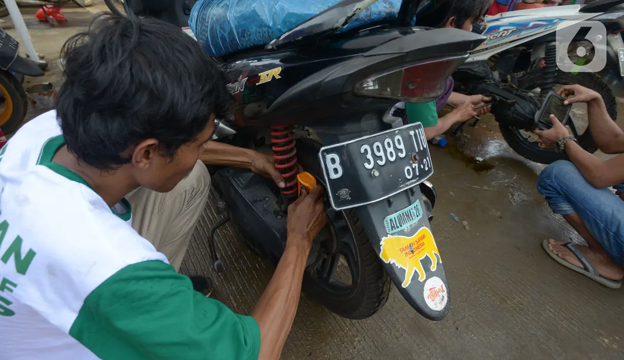 Motir memperbaiki sepeda motor korban banjir pada layanan bengkel gratis Badan Amil Zakat Nasional (BAZNAS) di Kampung Pulo, Jakarta, Sabtu (4/1/2020). Layanan bengkel gratis ini banyak dimanfaatkan korban banjir untuk memperbaiki sepeda motornya yang sempat terendam. (merdeka.com/Imam Buhori)