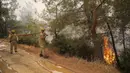 Petugas pemadam kebakaran bekerja di daerah Mazi yang diselimuti asap saat kebakaran hutan berguling menuruni bukit menuju pantai di Bodrum, Mugla, Turki, Minggu (1/8/2021). Menurut para pejabat, lebih dari 100 kebakaran hutan telah dikendalikan di Turki. (AP Photo/Emre Tazegul)