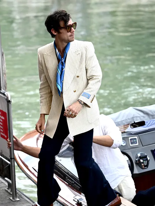 Harry Styles tiba di dermaga Hotel Excelsior selama Venice Film Festival 2022 ke-79 di Venesia, Italia (5/9/2022). Harry yang menandai peran utama pertamanya di film ini, tampak tamapn dalam nuansa gaya tahun 70-an. (AFP/Marco Bertorello)