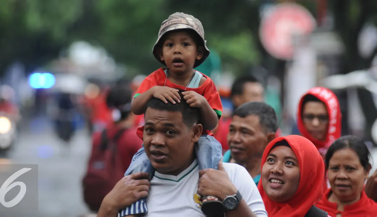 Pendukung Timnas Indonesia membopong anak saat berjalan menuju Stadion Pakansari, Bogor (3/12). Timnas Indonesia akan melakoni laga semifinal pertama Piala AFF 2016 melawan Vietnam di Stadion Pakansari Kab Bogor. (Liputan6.com/Helmi Fithriansyah)