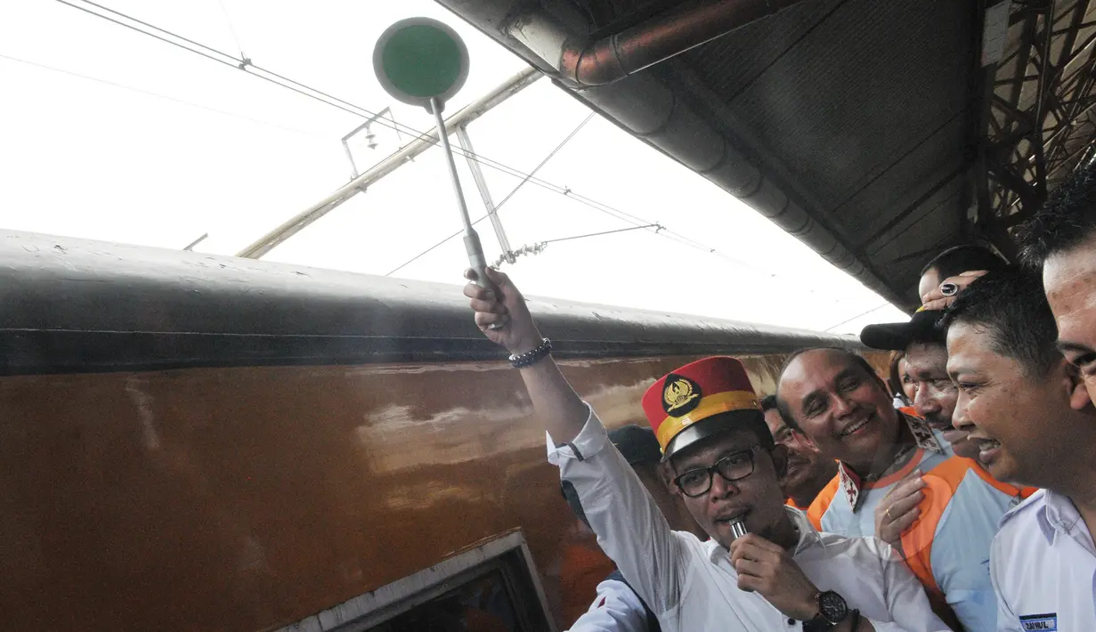 Menaker Hanif Dhakiri (kiri) menyilakan kereta api untuk berangkat di Stasiun Pasar Senen, Jakarta, Jumat (1/5). Menaker memperingati Hari Buruh se-Dunia (May Day) dengan mengangkat tema "Bersih-bersih BUMN". (Liputan6.com/Herman Zakharia)