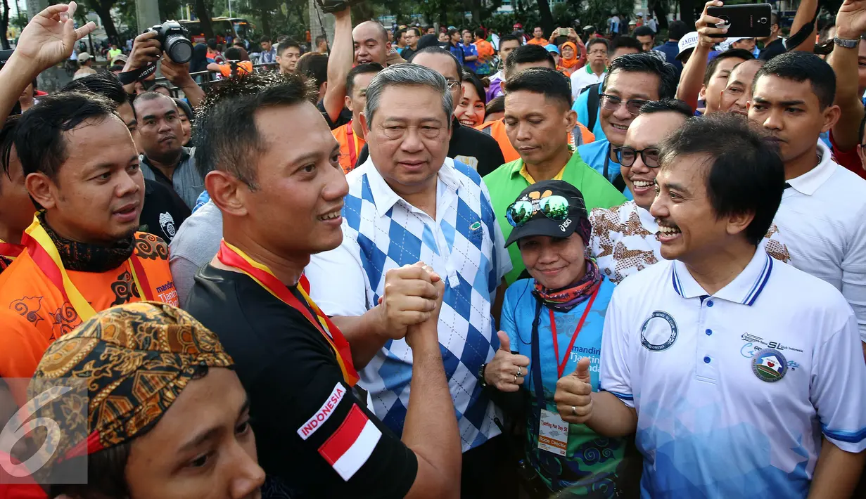 Calon Gubernur DKI Jakarta Agus Harimurti Yudhoyono melakukan salam komado dengan SBY saat menyapa warga Jakarta di Car Free Day (CFD), Senayan, Minggu (2/10). (Liputan6.com/Johan Tallo)