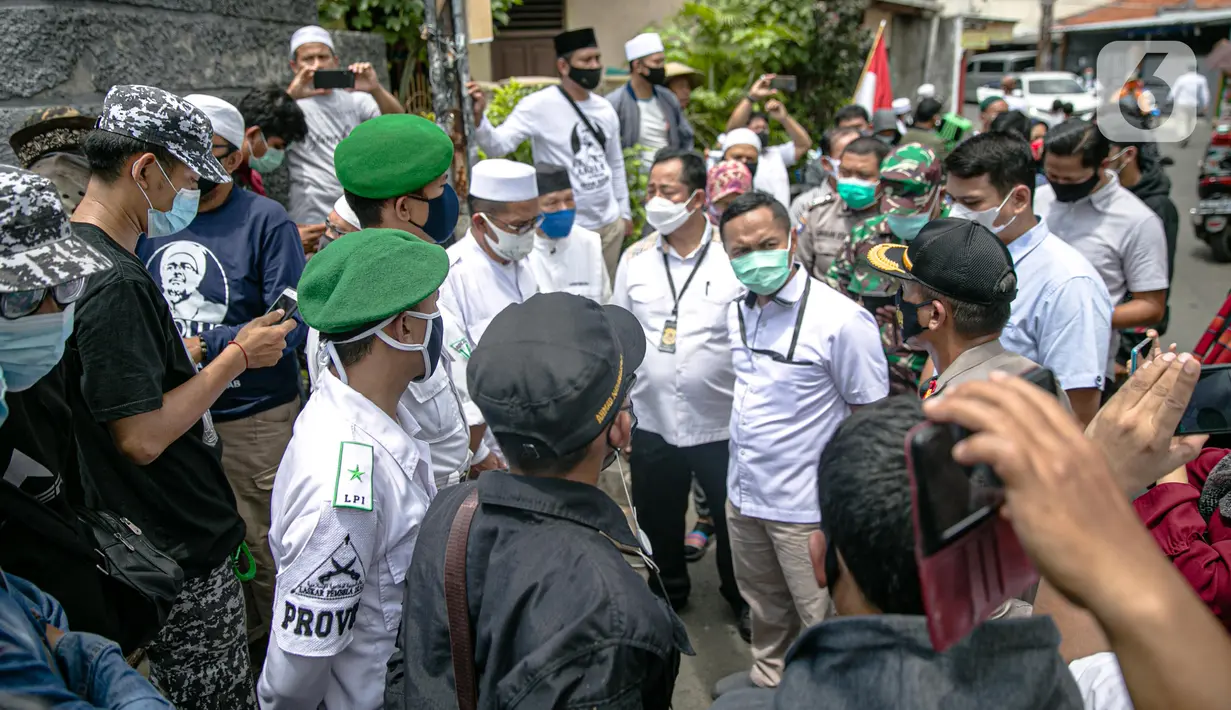 Anggota FPI mengadang anggota Polda Metro Jaya yang ingin memberi surat pemanggilan kepada Rizieq Shihab di kediamannya di Petamburan, Jakarta, Rabu (2/12/2020). Polisi kembali memanggil Rizieq Shihab terkait acara Maulid Nabi dan resepsi putrinya. (Liputan6.com/Faizal Fanani)