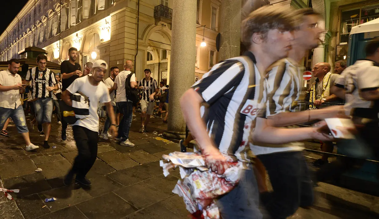 Para supporter tampak berlari panik usai terjadi ledakan saat nonton bareng final Liga Champions di Piazza San Carlo, Turin, Sabtu (3/6/2017). Acara nobar dipadati sekitar 20.000 supporter Juventus. (AFP/Massimo Pinca)