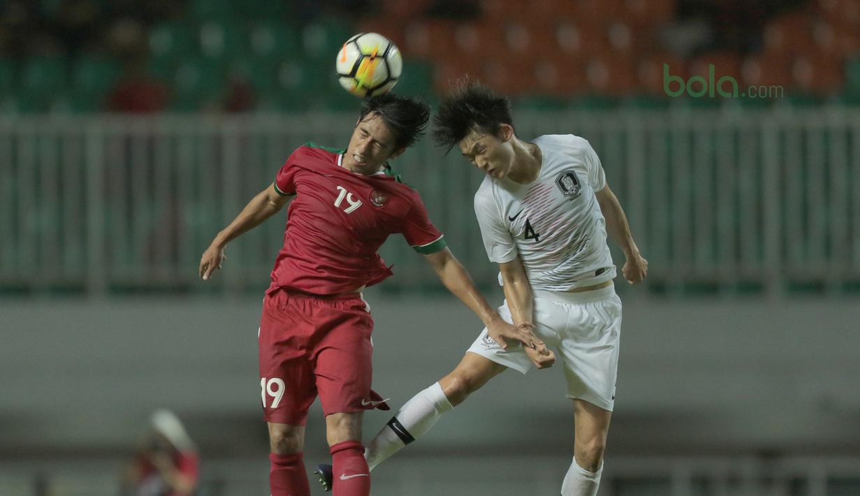Duel pemain Timnas Indonesia U-23, Hanif Syahbandi (kiri) dengan pemain Korea Selatan U-23, Lee Seung-mo pada laga uji coba di Stadion Pakansari, Bogor, (23/6/2018).  Indonesia U-23 kalah 1-2 dari Korea U-23. (Bola.com/Nick Hanoatubun)
