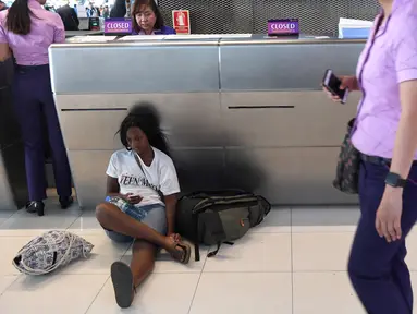 Penumpang beristirahat di area check-in di Bandara Internasional Suvarnabhumi di Bangkok (28/2). Puluhan penerbangan menuju Eropa dibatalkan setelah Pakistan menutup wilayah udaranya karena ketegangan dengan India meningkat. (AFP Photo/Lillian Suwnrumpha)