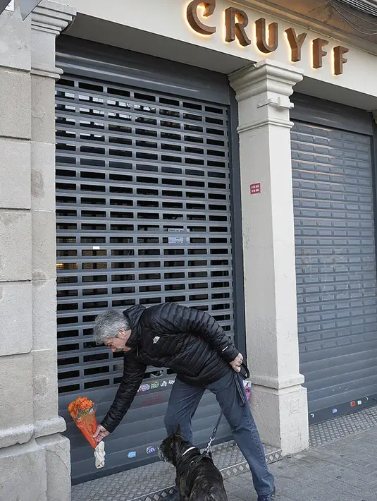 Seorang pria meletakan bunga di depan Cruyff Store, Barcelona, Kamis (24/3/2016). Johan Cruyff juga pernah tiga kali meraih gelar Ballon d'Or. (AFP/Lluis Gene)