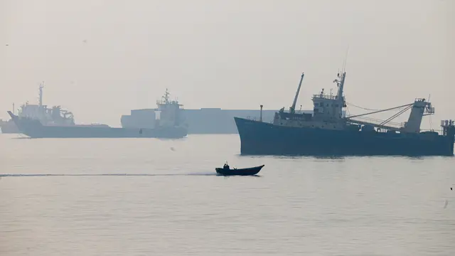 A motorboat travels past commercial vessels appear anchored in the Strait of Hormuz off Bandar Abbas, Iran, Monday, Tuesday, Oct, 6, 2026. (Amirhosein Khorgooi/ISNA via AP)