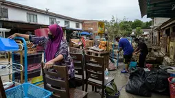 Warga membersihkan barang-barang setelah banjir surut di Mentakab, negara bagian Pahang, Malaysia (11/1/2020). Hujan deras yang terus melanda beberapa bagian jalan raya Pantai Timur di Pahang membuat daerah tersebut terendam banjir parah. (AFP/Mohd Rasfan)