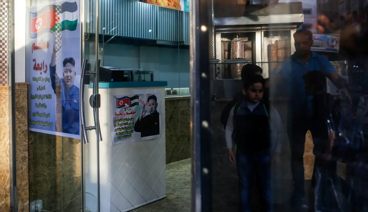 Poster pemimpin Korea Utara Kim Jong-un dan bendera Palestina di pintu restoran Rabaa di Gaza, Minggu (17/12). Restoran Raba memberikan diskon bagi pelanggan asal Korut sebagai apresiasi bagi sikap Kim Jong-un untuk Palestina. (MOHAMMED ABED/AFP)