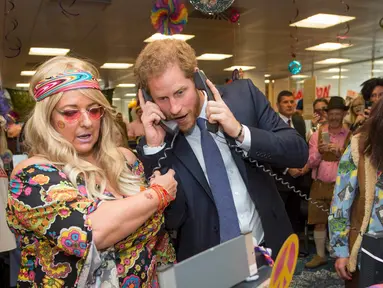 Pangeran Harry mengangkat dua telepon sekaligus saat menjadi broker dalam acara amal tahunan ICAP di London, Rabu (7/12). Pangeran Harry menjadi broker dadakan untuk mengumpulkan dana amal dari 60 kantor di seluruh dunia. (REUTERS/Geoff Pugh/Pool)
