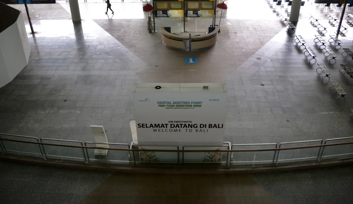 Seseorang berjalan di area kedatangan internasional yang hampir kosong di bandara Ngurah Rai di Tuban dekat Denpasar di pulau resor Bali (5/10/2021).  Bandara Ngurah Rai akan kembali dibukan pada 14 Oktober untuk beberapa pelancong internasional. (AFP/Sony Tumbelaka)