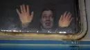 Seorang perempuan melihat ke arah kerabat dan menempelkan telapak tangannya ke jendela kereta menuju Lviv, di peron di Kiev, 3 Maret 2022. Sejumlah keluarga terpaksa terpisah, dengan mayoritas pria tetap tinggal di Ukraina untuk mempertahankan negaranya dari invasi Rusia.  (AP Photo/Vadim Ghirda)