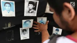 Aktivis melihat foto para korban HAM saat aksi Kamisan ke-538 di depan Istana Negara, Jakarta, Kamis (17/5). Aksi Kamisan tersebut sekaligus memeringati 20 tahun reformasi. (Liputan6.com/Immanuel Antonius)