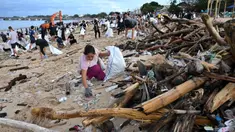Para relawan membersihkan sampah plastik dan lainnya yang terdampar di pantai Kedonganan, Kabupaten Badung, Bali, pada Sabtu 4 Januari 2025. (SONNY TUMBELAKA/AFP)