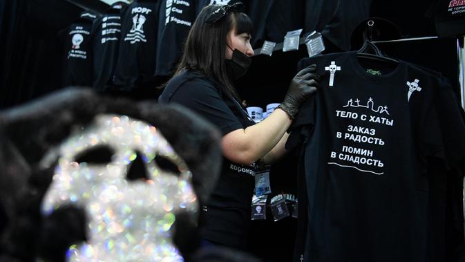 Seorang peserta menata kaus di stand selama pameran pemakaman di Moskow, Rusia pada Rabu (21/10/2020). (Photo by Kirill KUDRYAVTSEV / AFP)