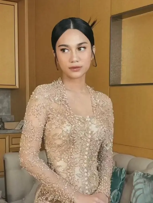 Ia kembali tampil dalam balutan kebaya nude, kali ini dalam model kutu baru yang minimalis. Kebayanya hadir dengan aksen kancing depan.  [@azizahsalsha_].