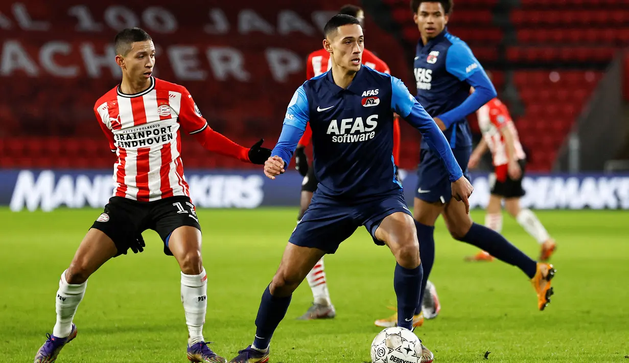 <p>Gelandang AZ Alkmaar, Tijjani Reijnders (kanan) menguasai bola dibayangi gelandang PSV Eindhoven, Mauro Junior pada laga Liga Belanda 2020/2021 di Philips Stadium, Eindhoven (13/1/2021). Tijjani Reijnders dipromosikan untuk bermain di tim utama AZ Alkmaar sejak tengah musim 2017/2018. Ia sempat dipinjamkan selama setengah musim ke RKC Waalwijk mulai 2 Januari hingga 30 Juni 2020. (AFP/ANP/Maurice van Steen)</p>