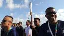 Aktor Hamish Daud (tengah) membawa obor pada kirab obor Asian Games 2018 di Pantai Kuta, Bali, Senin (23/7). Hamish menerima obor yang diserahkan oleh Menko Bidang Pembangunan Manusia dan Kebudayaan, Puan Maharani. (AFP/SONNY TUMBELAKA)