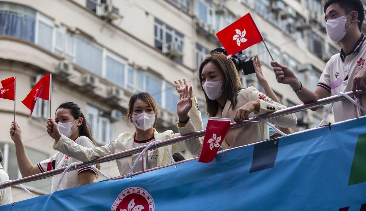 Anggota delegasi Olimpiade Hong Kong mengibarkan bendera selama parade bus, setelah Olimpiade Tokyo 2020, di Hong Kong, Kamis (19/8/2021). Hong Kong yang memiliki 46 atlet perwakilan pada Olimpiade Tokyo 2020 berhasil mengumpulkan satu emas, dua perak dan tiga perunggu. (ISAAC LAWRENCE/AFP)