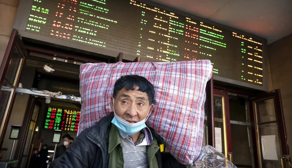 Seorang pelancong yang mengenakan masker untuk melindungi dari penyebaran virus corona membawa kopernya saat dia berjalan keluar dari pintu keluar di Stasiun Kereta Api Beijing di Beijing, Kamis (28/1/2021).  (AP Photo/Mark Schiefelbein)