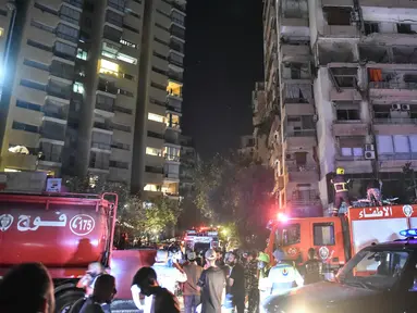 Petugas pemadam kebakaran berkumpul di lokasi gedung apartemen yang terkena serangan udara Israel di distrik Cola, Beirut, 30 September 2024. (Fadel ITANI/AFP)