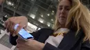 Manajer pemasaran, Amanda Back memindai dengan smartphone sebuah microchip yang dikembangkan oleh perusahaan DSruptive Subdermals dan ditanamkan di tangannya untuk mengungkapkan kartu kesehatannya di Epicenter Stockholm (20/12/2021). (AFP/Viken Kantarci)