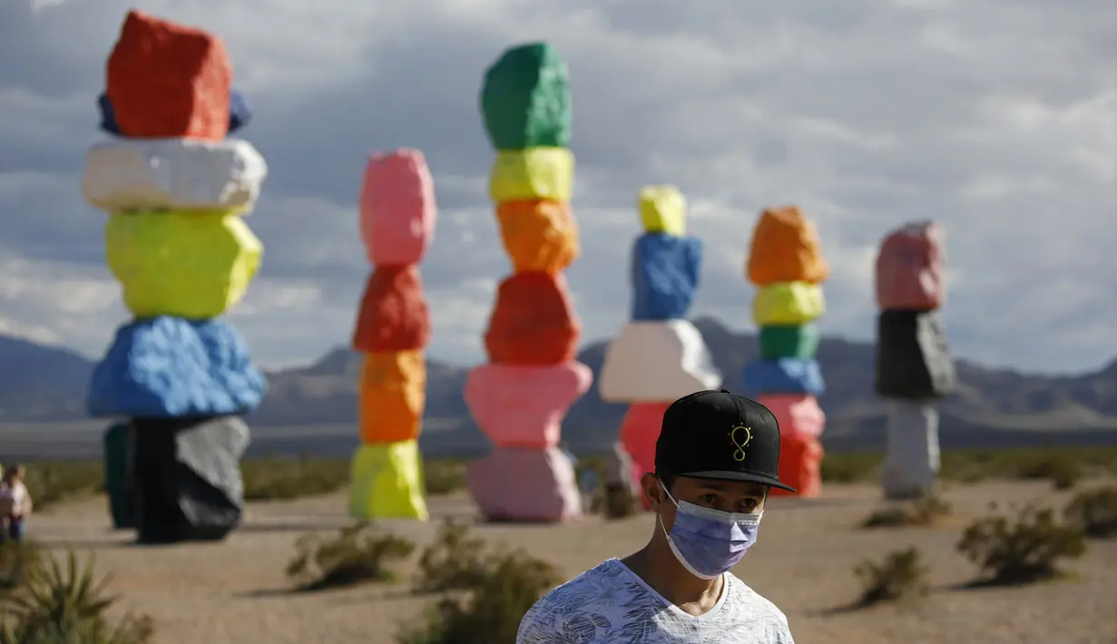 Seorang pria berjalan di instalasi seni Seven Magic Mountains karya seniman Ugo Rondinone di Las Vegas, Amerika Serikat, Selasa (7/4/2020). Seven Magic Mountains mulai dibuka untuk umum pada bulan Mei 2016 lalu. (AP Photo/John Locher)