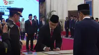 Kepala BPOM Taruna Ikrar menandatangani surat pelantikan di hadapan Presiden Jokowi, Senin (19/8/2024). (Tangkapan layar Youtube Sekretariat Presiden)