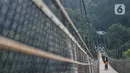 Pengunjung melintasi Jembatan Gantung Situ Gunung di Sukabumi, Minggu (20/9/2020). Dari rata-rata 2.500 pengunjung tiap harinya kini hanya di bawah 1.000 pelancong per hari akibat merebaknya pandemi Covid-19 serta adanya penerapan PSBB. (merdeka.com/Iqbal S. Nugroho)