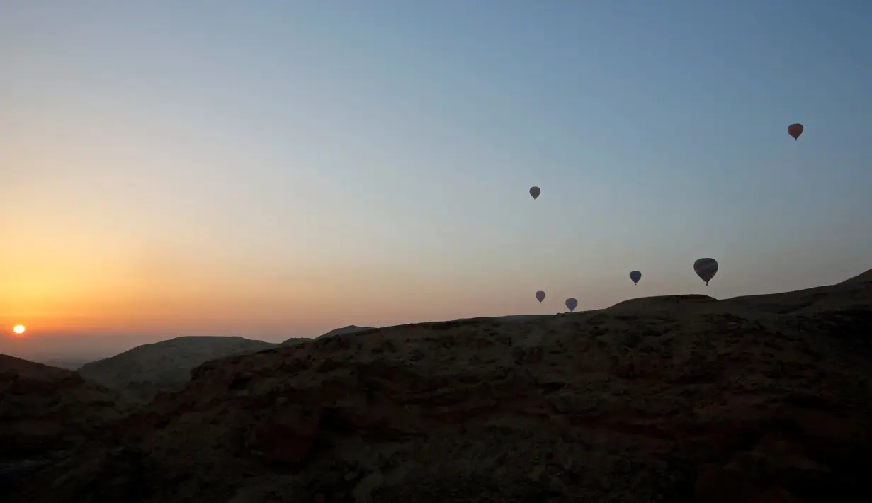 Sejumlah balon udara yang membawa wisatawan terbang saat matahari terbit di atas kota Luxor, Kairo, Mesir (13/12). Luxor adalah sebuah kota modern yang terletak di kedua tepi timur dan barat Sungai Nil di Mesir bagian utara. (Reuters/Amr Abdallah Dalsh)