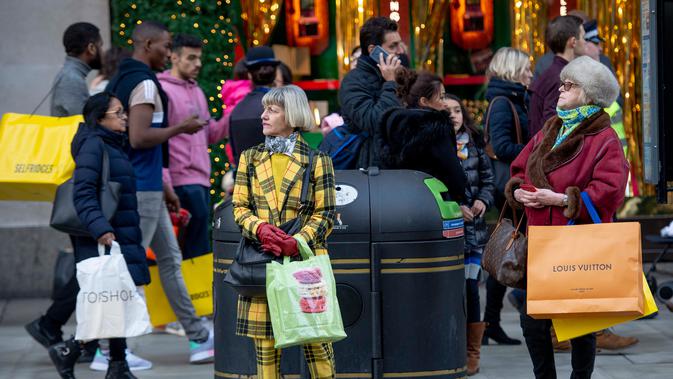 Pembeli berdiri sambil membawa kantong belanjaan di Oxford Street, London pada Sabtu (22/12). Setiap hari Oxford Street yang merupakan salah satu pusat perbelanjaan selalu ramai, namun menjelang natal keramaiannya meningkat. (NIKLAS HALLE'N/AFP)