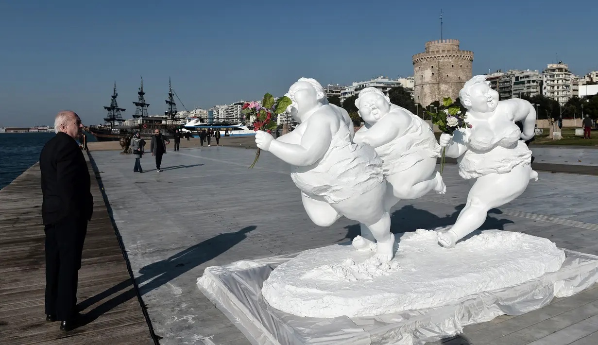Seorang pria mengamati patung karya seniman China Xu Hongfei di Thessaloniki, Yunani, Rabu (19/12). Patung-patung karya Xu Hongfei tersebut dipamerkan pada 17-24 Desember 2018. (Sakis Mitrolidis/AFP)
