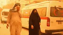 Orang-orang berjalan di jalan saat badai pasir melanda Baghdad, Irak, Senin, 16 Mei 2022. Badai pasir yang melanda Irak mengirim sedikitnya 2.000 orang ke rumah sakit dengan masalah pernapasan dan menyebabkan penutupan bandara, sekolah dan umum kantor di seluruh negeri. (AP Photo/Hadi Mizban)