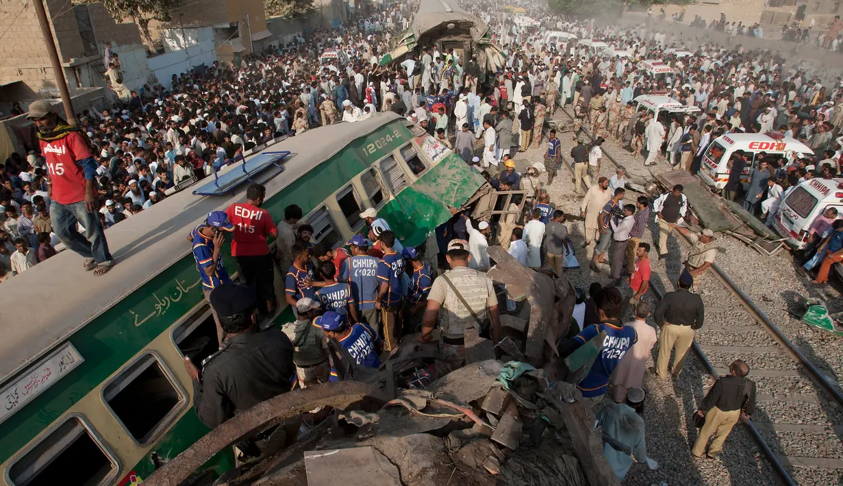 Petugas dibantu warga mengevakuasi korban kecelakaan kereta di Karachi, Pakistan, Kamis (3/11). Kecelakaan itu terjadi akibat kereta penumpang Farid Express bertabrakan dengan kereta penumpang Zakria Express. (AP Photo/Shakil Adil)