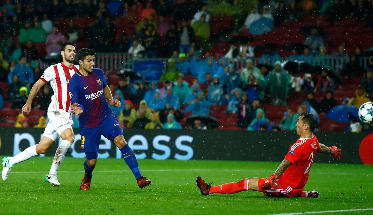 Pemain Barcelona, Luis Suarez menendang bola yang berusaha dihadang kiper Olympiakos, Silvio Proto dalam fase grup Liga Champions di Camp Nou, Kamis (19/10). Barca menang 3-1 pada laga yang diwarnai kartu merah terhadap Gerard Pique.  (AP/Manu Fernandez)