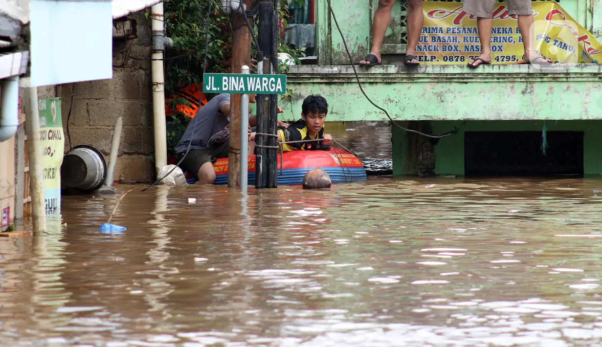 Warga menggunakan perahu karet berusaha keluar dari salah satu gang di Kawasan Rawajati yang tergenang banjir, Jakarta, Rabu Rabu (1/1/2020). Hujan yang mengguyur Jakarta sejak Selasa sore (31/12/2019) mengakibatkan banjir di sejumlah titik di Jakarta. (Liputan6.com/Helmi Fithriansyah)