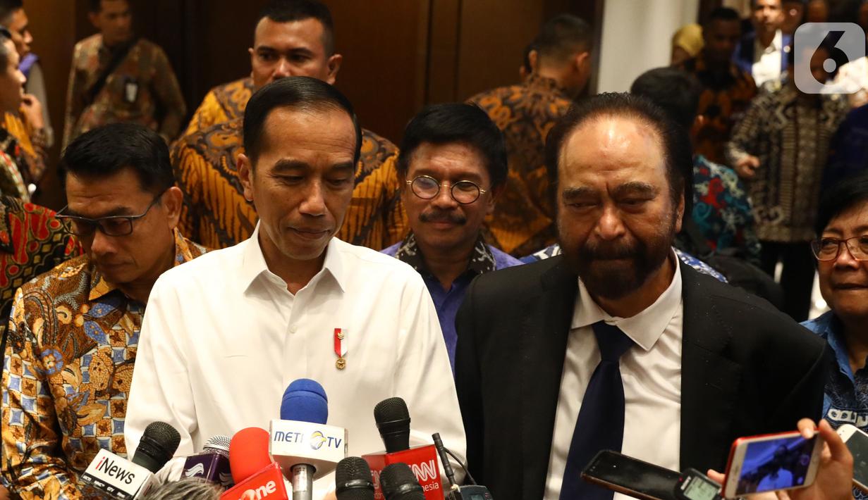 Presiden Joko Widodo atau Jokowi (kiri) didampingi Ketua Umum Partai Nasdem Surya Paloh (kanan) memberi keterangan saat menghadiri perayaan ulang tahun ke-8 Partai Nasdem di JIExpo, Jakarta, Senin (11/11/2019). Surya Paloh menyambut langsung kedatangan Jokowi di HUT Nasdem. (Liputan6.com/Angga Yunia