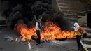 Demonstran dari oposisi Venezuela berada didekat kobaran api saat menggelar aksinya menentang Presiden Nicolas Maduro di Caracas, Venezuela (24/4). (AFP/Federico Parra)