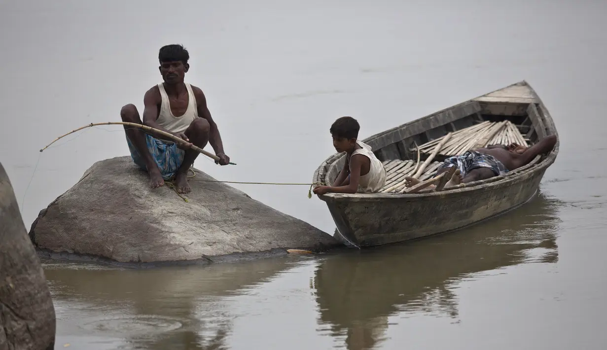 Seorang nelayan duduk di atas batu menangkap ikan di sungai Brahmaputra di desa Kasoshila di Gauhati, India (21/10/2019). Brahmaputra adalah salah satu sungai terbesar di Asia, yang melewati wilayah Tibet China, India, dan Bangladesh sebelum konvergen ke Teluk Benggala. (AP Photo/Anupam Nath)