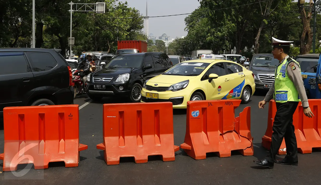 Petugas Satlantas melakukan penutupan Jalan Medan Merdeka menuju Istana Negara, Jakarta, Jumat (30/10). Berbagai antisipasi dilakukan jajaran kepolisian untuk mengamankan jalannya aksi demo ribuan buruh di depan Istana. (Liputan6.com/Yoppy Renato)