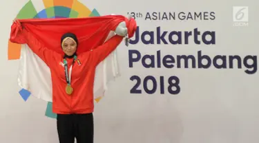 Pesilat Indonesia Sarah Tria Monita mengangkat bendera Merah Putih usai menaklukkan Nong Oy Vongphakdy asal Laos dalam babak final Kelas C Putri Asian Games 2018 di Jakarta, Senin (27/8). Sarah menang dan mendapatkan medali emas. (Merdeka.com/Arie Basuki)