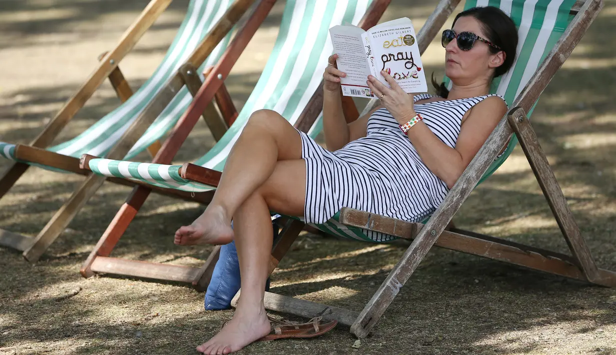 Seorang wanita membaca buku di kursi lipat pada saat cuaca hangat di taman Regents, London, Inggris, (24/8). (REUTERS/Neil Hall)