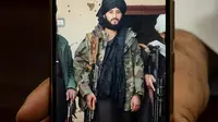 Foto yang diambil pada 18 Januari 2022 ini menunjukkan Wali Kota Maymana Damullah Mohibullah Mowaffaq memegang ponselnya dengan foto dirinya saat menjadi pejuang Taliban, di Maymana. (AFP)