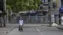 Seorang pria berjalan melalui jalan yang sepi setelah pemerintah memberlakukan pembatasan perjalanan dan lockdown akhir pekan di Kolombo, Sri Lanka, Sabtu (22/5/2021). Sri Lanka pada Jumat, 21 Mei mencatat 3.547 kasus harian corona Covid-19. (Ishara S. KODIKARA/AFP)