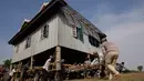 Sejumlah warga mendorong rumah di Desa Serey Andet di provinsi Kampong Speu, Kamboja (27/3). Mereka memindahkan rumah dengan cara tersebut dengan tujuan agar rumah tetap utuh. (AP Photo/Heng Sinith)